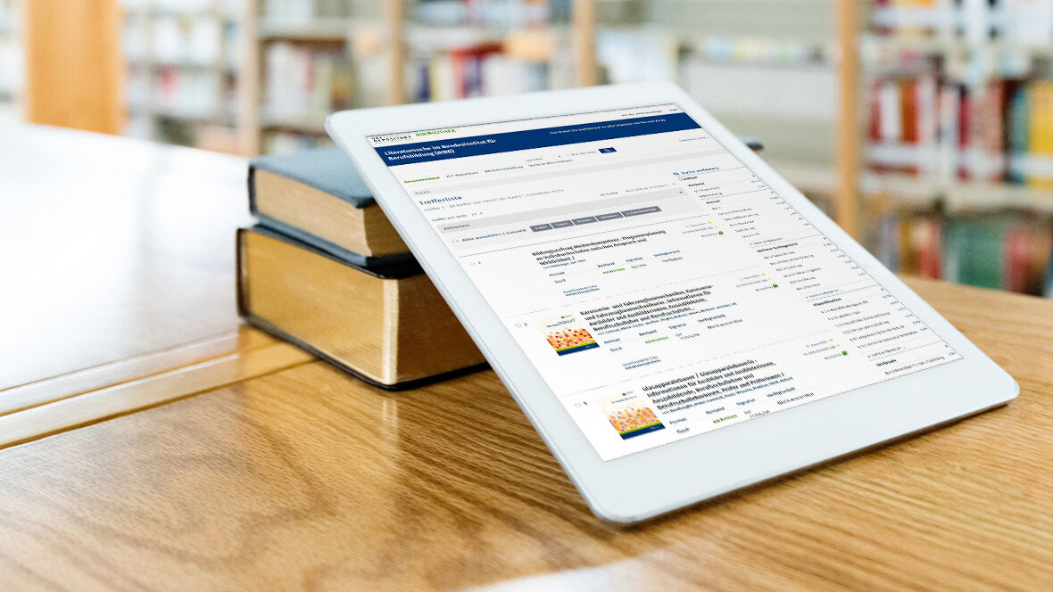 Ein iPad liegt an Bücher gelehnt auf einem Tisch in einer Bibliothek und zeigt die Webseite des VET Repository