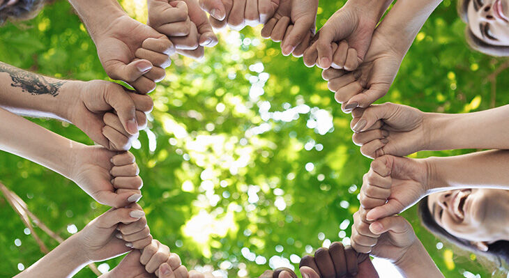 Viele Personen, die ihre Fäuste in einem Kreis zusammen halten, als Symbol des Zusammenhalts