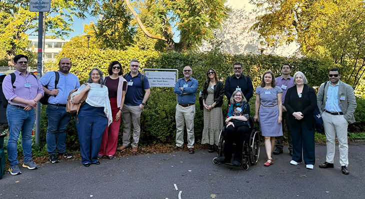 A group of people in front of the school building, with a sign reading ‘Robert-Wetzlar Vocational College of the City of Bonn, UNESCO Project School’
