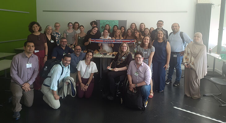 Group photo. In the centre, two people are holding a scarf bearing the inscription ‘Costa Rica’ 