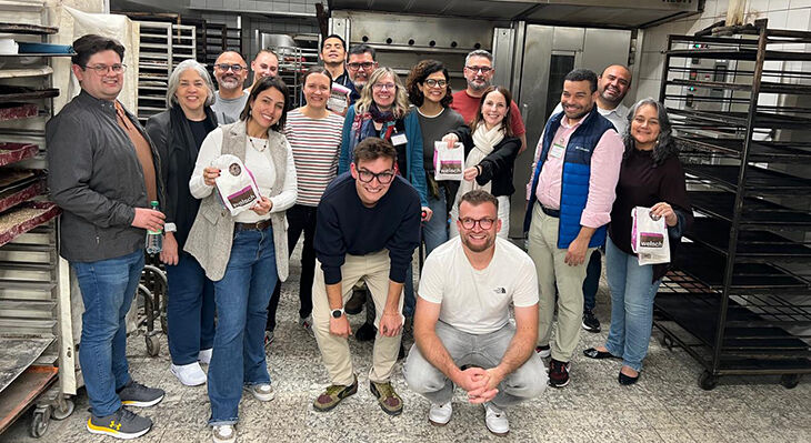 A group of people in front of an oven, some of them holding bakery bags.