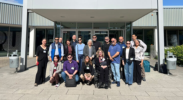 The group stands in front of the entrance to a building bearing the inscription ‘Campus Crafts Sector’ 