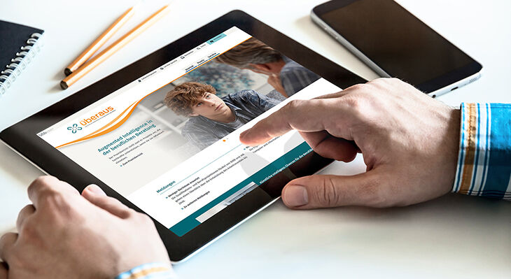 H&auml;nde bedienen Tablet mit ge&ouml;ffneter Webseite, auf der ein junger Mann zu sehen ist