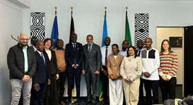 Gruppenfoto von 14 Personen in einem Konferenzraum. Im Hintergrund stehen die Flaggen der Europ&auml;ischen Union, Deutschlands, der Vereinten Nationen und der Afrikanischen Union.