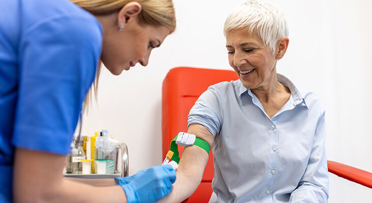 Eine Medizinische Fachangestellte nimmer einer Frau Blut ab