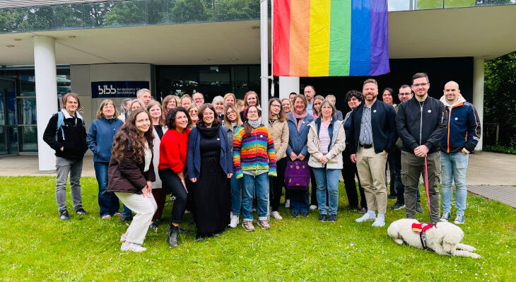 A group of BIBB employees standing in front of the rainbow flag outside the BIBB building