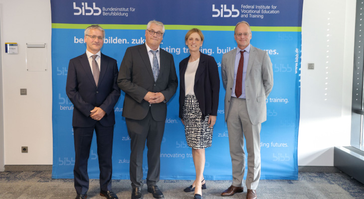 Vier Menschen stehen vor einer blauen BIBB-Fotowand