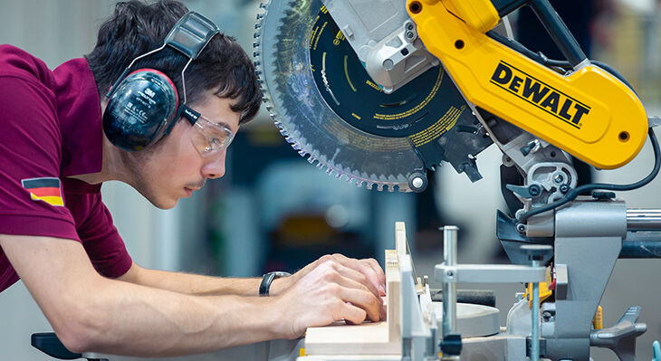 Ein deutscher Teilnehmer der WorldSkills Shanghai 2026 richtet konzentriert ein Holzst&uuml;ck an einer Kapp- und Gehrungss&auml;ge aus.