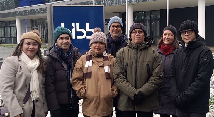 Group of people standing in front of the BIBB building wearing hats and thick jackets