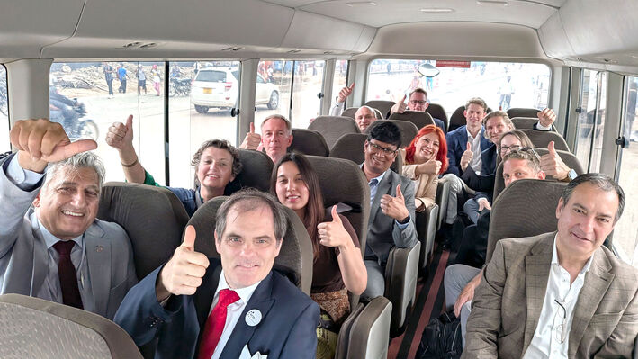 Delegation sitzt im Bus und alle strecken den Daumen in die Luft