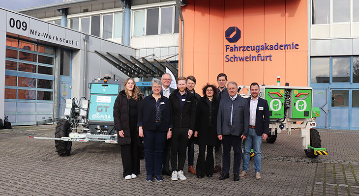 Eine Gruppe von Personen, die vor landwirtschaftlichen Robotern steht.