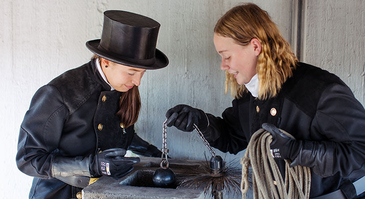 zwei angehende Schornsteinfegerinnen reinigen einen Schornstein