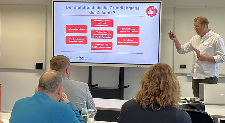 Ein Redner stellt die Präsentationsfolie zum Thema "Der metalltechnische Grundlehrgang der Zukunft?" vor. 