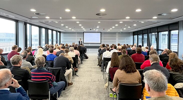 120 Personen sitzen in einem Plenarsaal nebeneinander.
