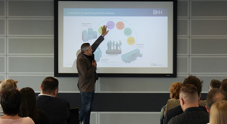 Prof. Dr. Henning Klaffke zeigt bei einem Vortrag auf eine Power-Point-Folie.