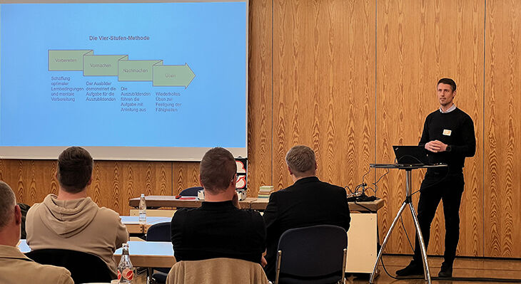 Eine Person hält eine Präsentation  vor mehreren Gästen.