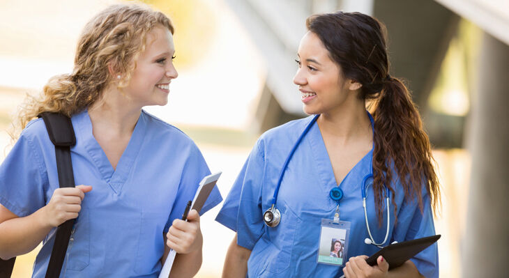 Zwei Frauen in Krankenschwesterkitteln unterhalten sich.