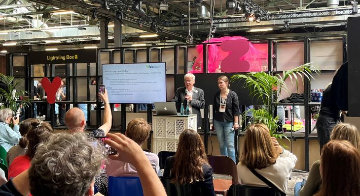 Personen vor einer Bühne während des Lightning-Talks.