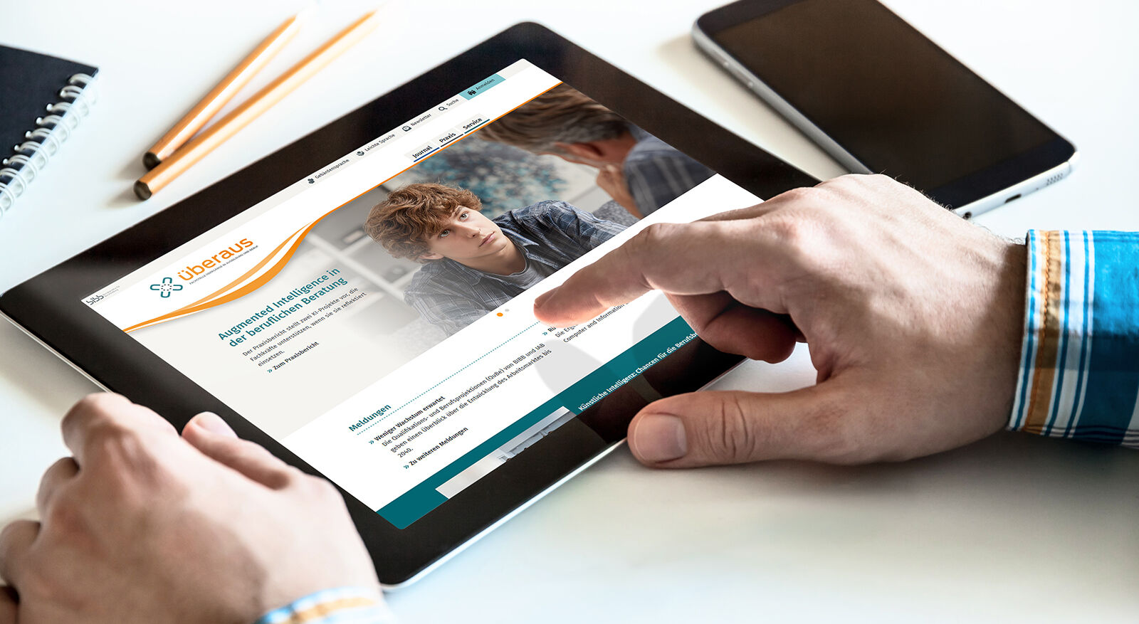 H&auml;nde bedienen Tablet mit ge&ouml;ffneter Webseite, auf der ein junger Mann zu sehen ist